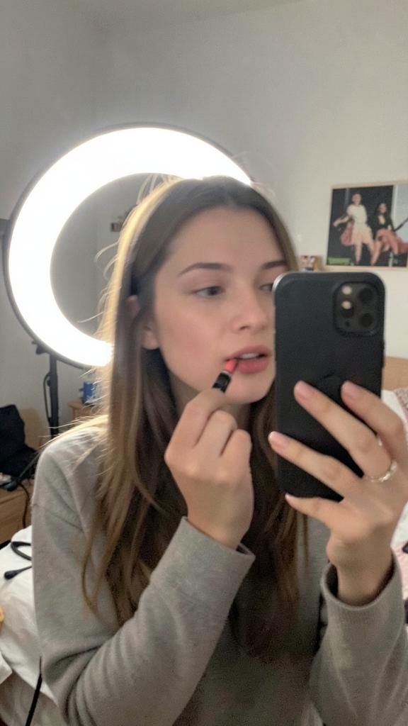 Creator applying lipstick while filming a vertical UGC clip